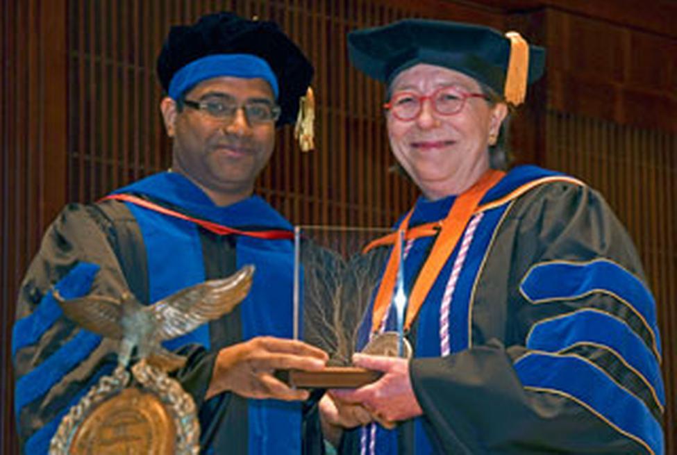 SBMI Alumnus (2015), Alumni Association member and assistant professor Deevakar Rogith, MBBS, PhD, presents the award to Dr. Johnson, May 9. (Photo by Dwight Andrews)